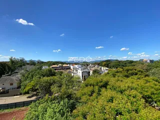 Vista panorâmica de uma área residencial com vegetação densa e colinas ao fundo.