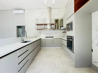 Esta é uma foto de uma cozinha moderna com armários brancos e bancadas claras.