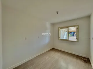 Ambiente interno de uma sala com piso de madeira clara e paredes brancas.