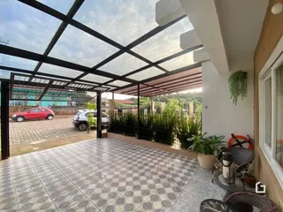 Área externa pavimentada sob uma estrutura de pérgula.