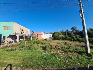 Vista externa de uma propriedade com jardim e vegetação ao fundo.