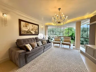 Sala de estar ampla com sofá cinza e vista para a área externa verde.