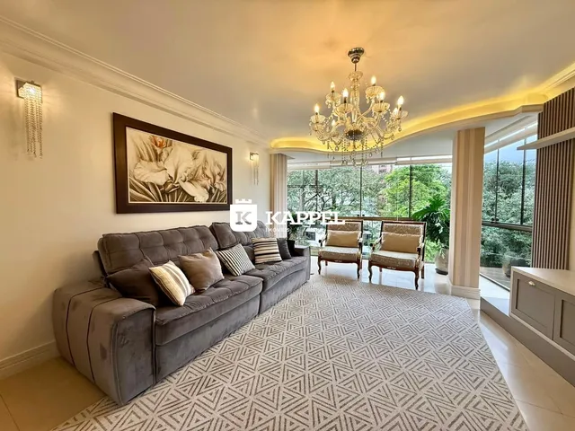Sala de estar ampla com sofá cinza e vista para a área externa verde.