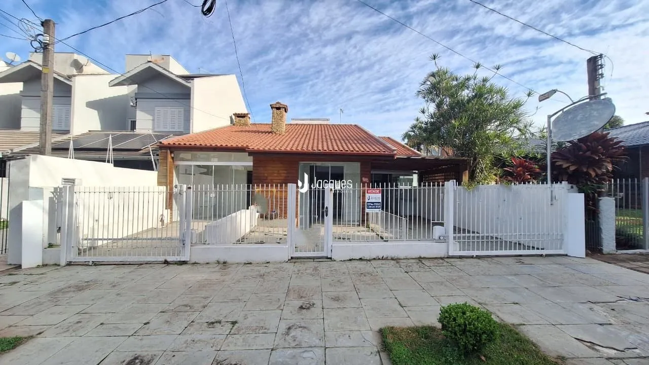 Fachada de uma residência em Lajeado, Brasil, com muro e portão branco.