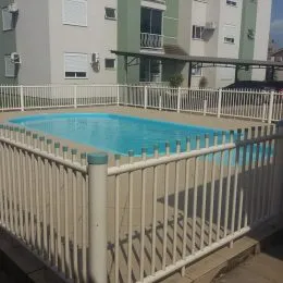 Foto de uma piscina externa cercada por uma grade branca.