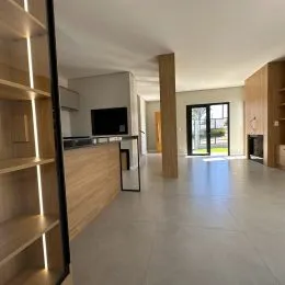 Ambiente interno com painéis de madeira e televisão em um espaço aberto.