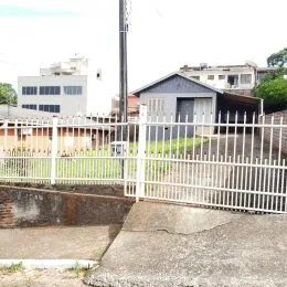 Vista externa de uma propriedade com cerca branca no primeiro plano.