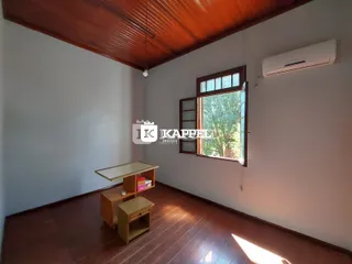 Sala de estar com piso de madeira e janela com caixilhos de madeira.