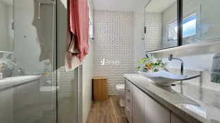 Interior de um banheiro moderno com revestimento de azulejo branco e piso de madeira.