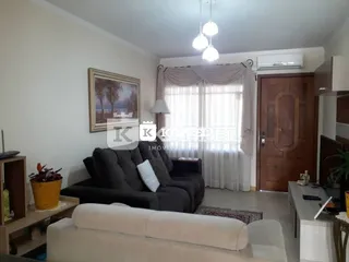 Foto de uma sala de estar com sofá e cortinas claras.
