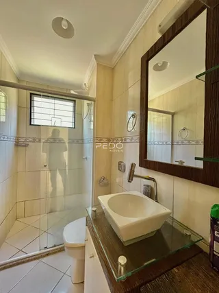 Foto de um banheiro com revestimento cerâmico e box de vidro.