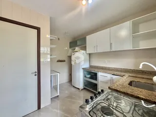 Foto de uma cozinha com armários brancos e piso claro.