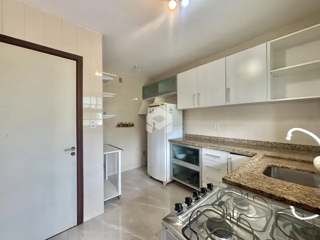 Foto de uma cozinha com armários brancos e piso claro.