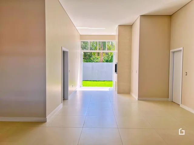 Corredor interno de uma residência com piso claro e paredes bege.