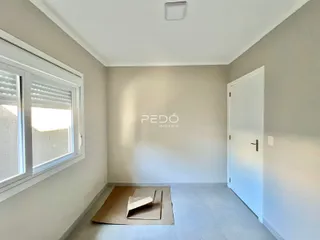 Interior de um cômodo com parede lisa e janela no ambiente.