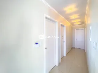 Corredor interno de um apartamento com paredes brancas e portas brancas.