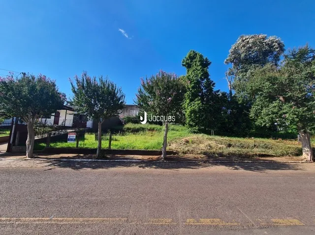 Vista externa de uma propriedade com vegetação e estrada no primeiro plano.