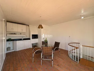 Ambiente de sala de jantar e cozinha com piso de tijolo aparente.