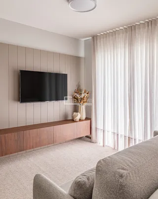 Sala de estar com sofá e televisão montada na parede.
