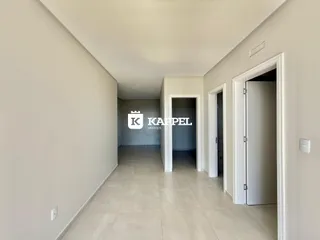 Corredor interno de um imóvel com piso claro e paredes brancas.