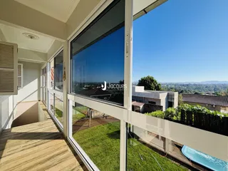 Vista da sala de estar com janelas amplas para um jardim gramado.