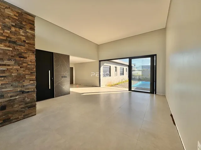 Ambiente interno de uma sala de estar com piso de porcelanato claro e parede de pedra.