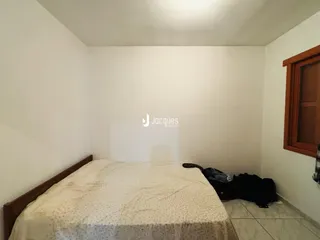 Quarto com cama e paredes brancas.