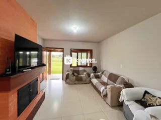 Sala de estar com sofá e televisão em um ambiente claro.