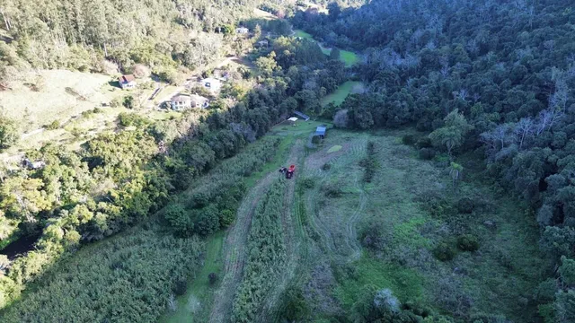 Vista aérea de uma área rural com vegetação densa e um caminho de terra.