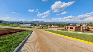 Vista externa de uma estrada rural com vegetação e colinas ao fundo.