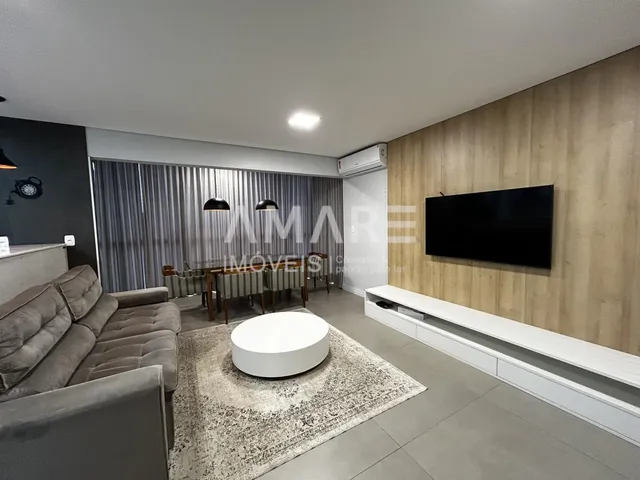Sala de estar moderna com sofá e televisão montada na parede.