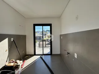 Vista interna de um ambiente com piso de cerâmica e porta de vidro.