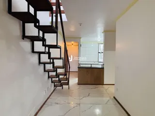 Hall de entrada com escadaria de madeira e piso de porcelanato claro.