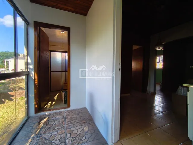 Vista interna de um corredor com piso de cerâmica e porta de madeira.