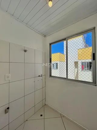 Vista interna de um corredor com paredes brancas e piso de cerâmica.