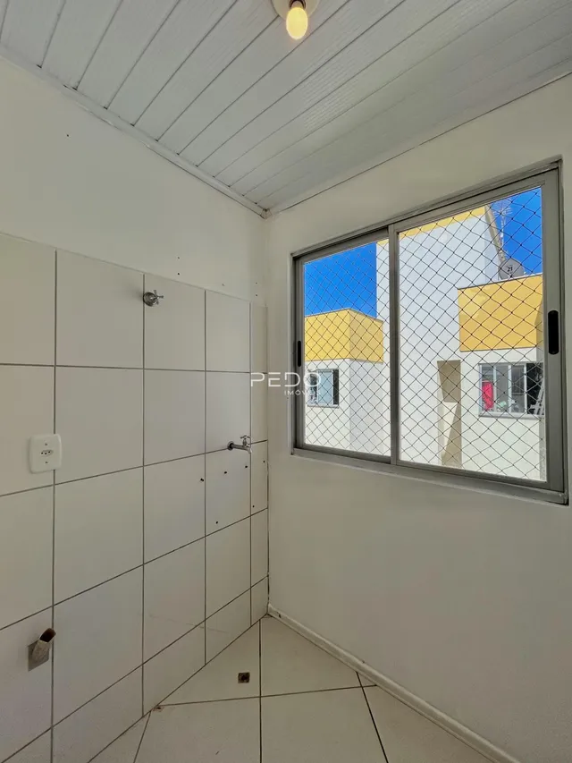 Vista interna de um corredor com paredes brancas e piso de cerâmica.