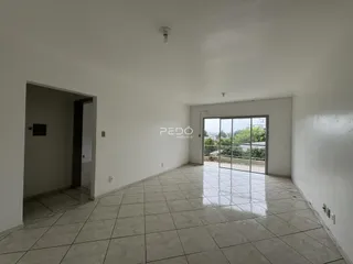 Interior de uma sala ampla com piso de cerâmica e porta de vidro.