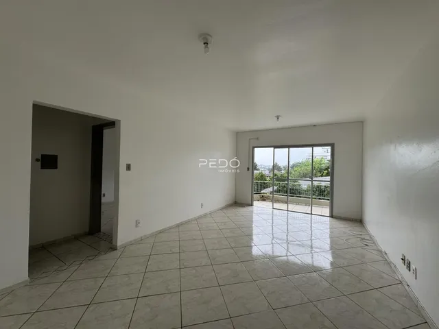 Interior de uma sala ampla com piso de cerâmica e porta de vidro.