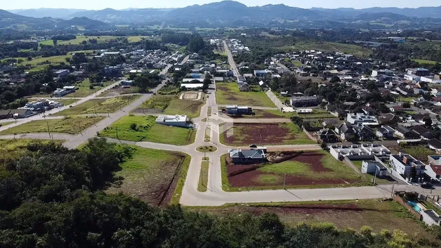 Vista aérea de uma área residencial com campos e estradas no entorno.