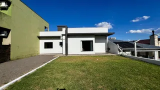 Fachada de uma casa moderna branca com gramado verde em Lajeado.