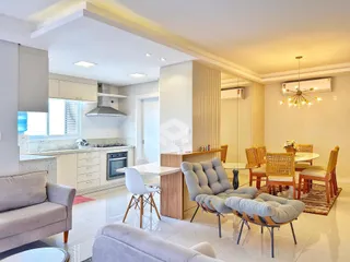 Sala de estar com cozinha integrada e área de jantar em um apartamento em Lajeado.