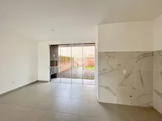 Ambiente interno com piso de cerâmica e porta de vidro que dá acesso ao quintal.