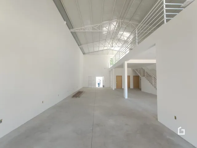 Interior de um espaço com teto exposto e paredes brancas.