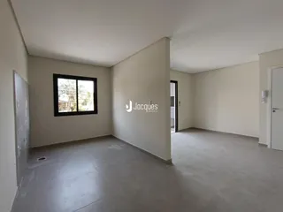 Vista interna de um cômodo com paredes brancas e piso de concreto.