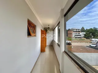 Corredor interno de um imóvel com piso claro e paredes brancas.
