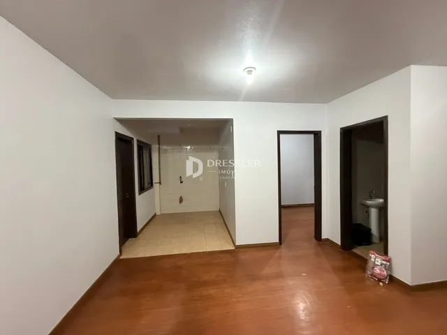 Hall de entrada com piso de madeira e paredes brancas.