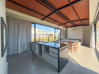 Ambiente interno de uma sala de estar com grandes janelas e teto de madeira exposta.