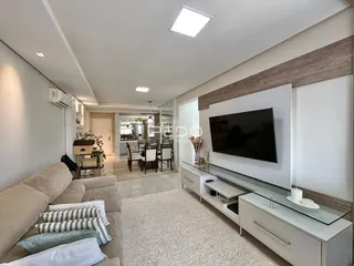 Sala de estar moderna com sofá e televisão em um imóvel no Brasil.