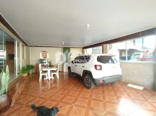 Imagem de uma área interna com piso de cerâmica e um veículo branco estacionado.