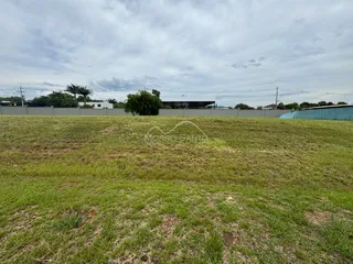 Vista externa de um terreno com grama verde sob um céu nublado.